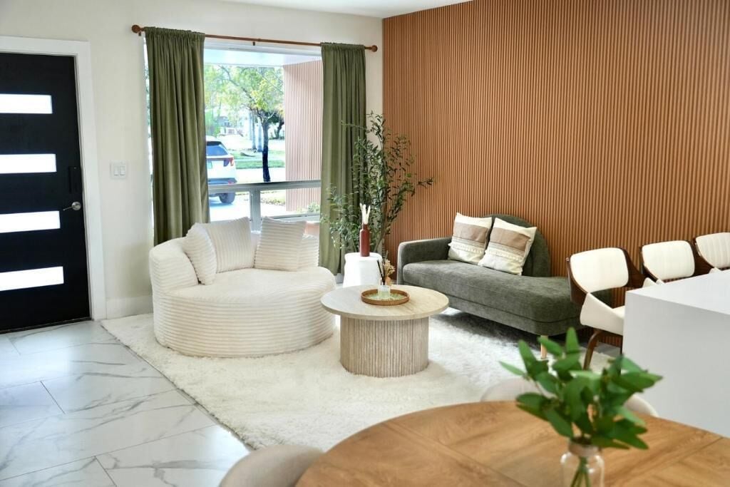 A modern living room with a round coffee table, two sofas, a white rug, and a wooden wall panel.