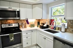 A modern kitchen with white cabinets, a microwave, stove, and a sink. - Luxury Escape w/ Pool & Billiards • Near Beach (Hollywood)