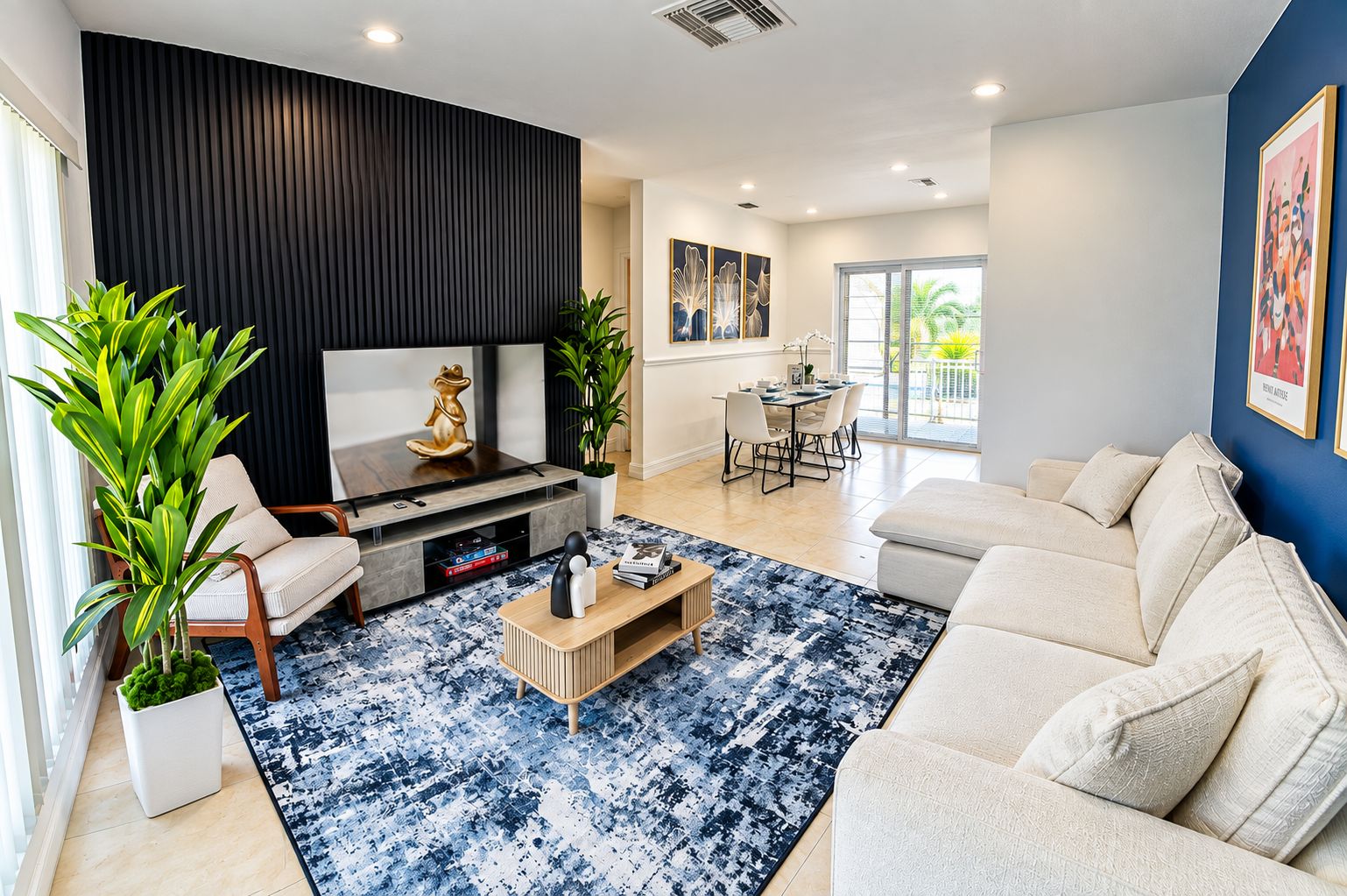 A modern living room with a flat-screen TV, a coffee table, a sofa, and a dining area with a table and chairs.