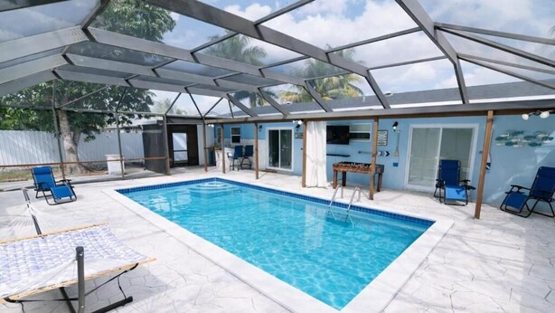 Una piscina techada con sillones de descanso, una mesa y un espacio de patio.