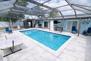 Ein überdachter Swimmingpool mit Liegestühlen, einem Tisch und einer Terrassenanlage.