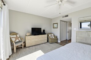 A bedroom with a bed, a television on a dresser, a chair, and a dresser. - Welcome to Villa E-6! (St. George Island)