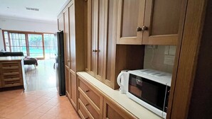 A kitchen with wooden cabinets, a microwave, and a refrigerator.