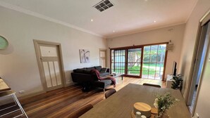 A spacious living area with a wooden floor, a sofa, a coffee table, and a view through large glass doors.