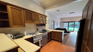 A kitchen with wooden cabinets, a gas stove, a sink, and a refrigerator.