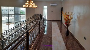 A spacious hallway with a marble floor, a decorative chandelier, and a view of the outside through large windows.