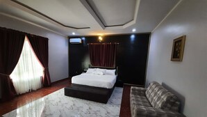 A modern bedroom with a large bed, a sofa, a marble floor, and a ceiling with recessed lighting.