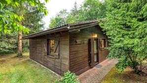 Eine kleine Holzhütte mit geneigtem Dach, einer Tür und einem Fenster.