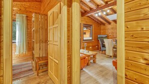 A wooden cabin interior with a dining area, a window with curtains, and a ceiling with exposed beams. - Stunning home in Merzalben with sauna (Merzalben)