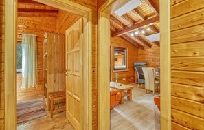 Ein Holzblockbau-Innenraum mit Essbereich, einem Fenster mit Vorhängen und einer Decke mit freiliegenden Balken.
