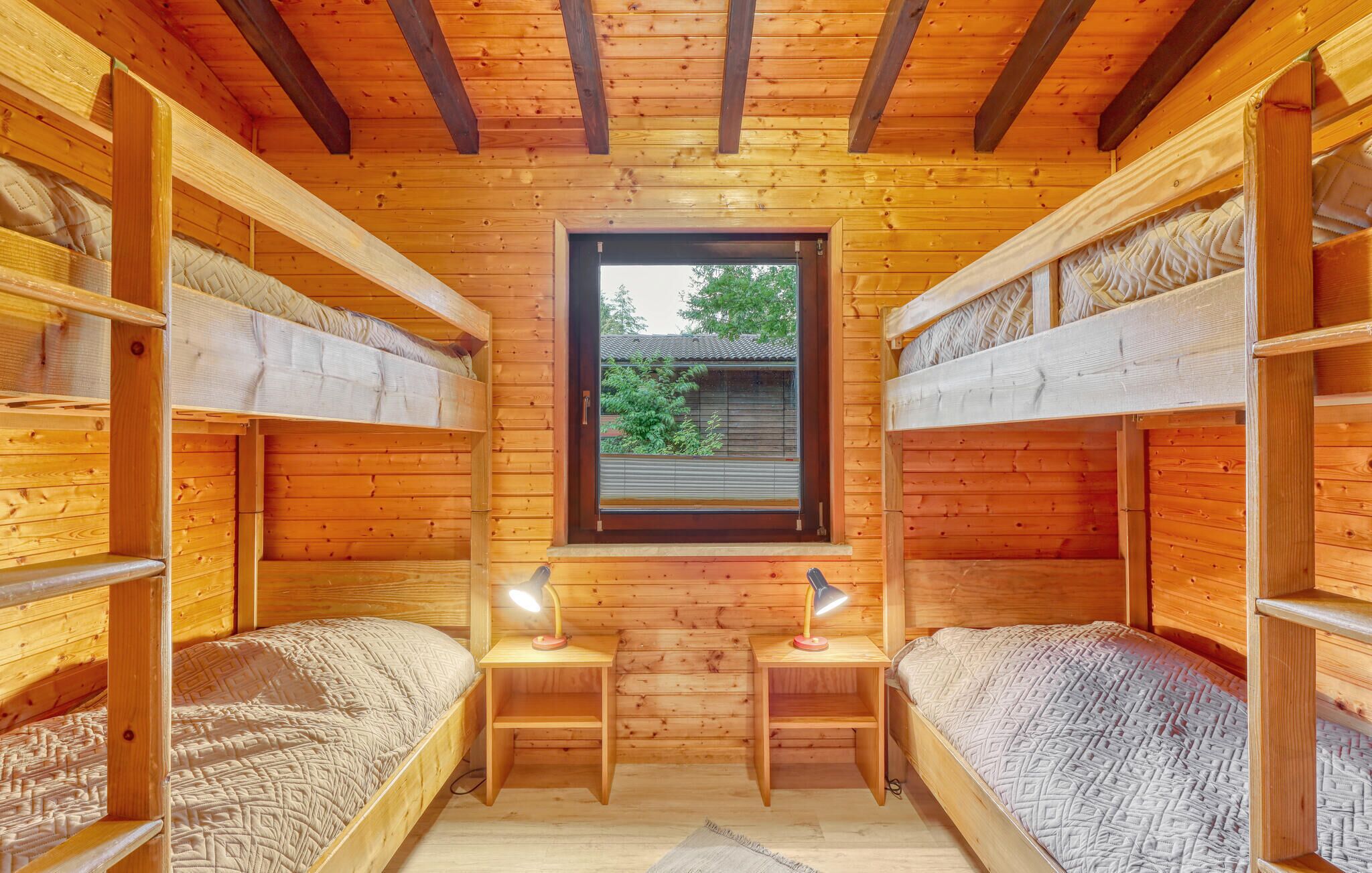 A wooden cabin with bunk beds, a window, and two bedside lamps.