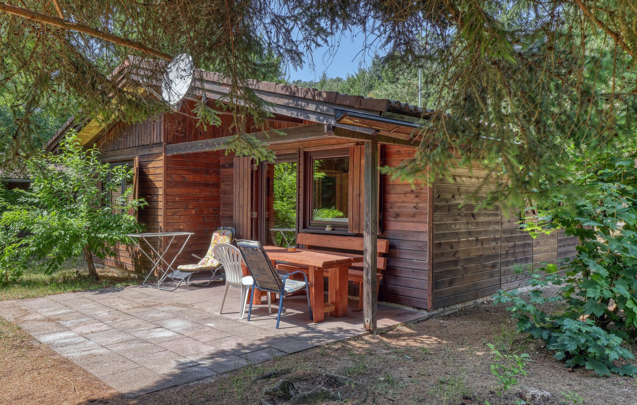 Une cabane en bois avec un patio, une table et deux chaises.