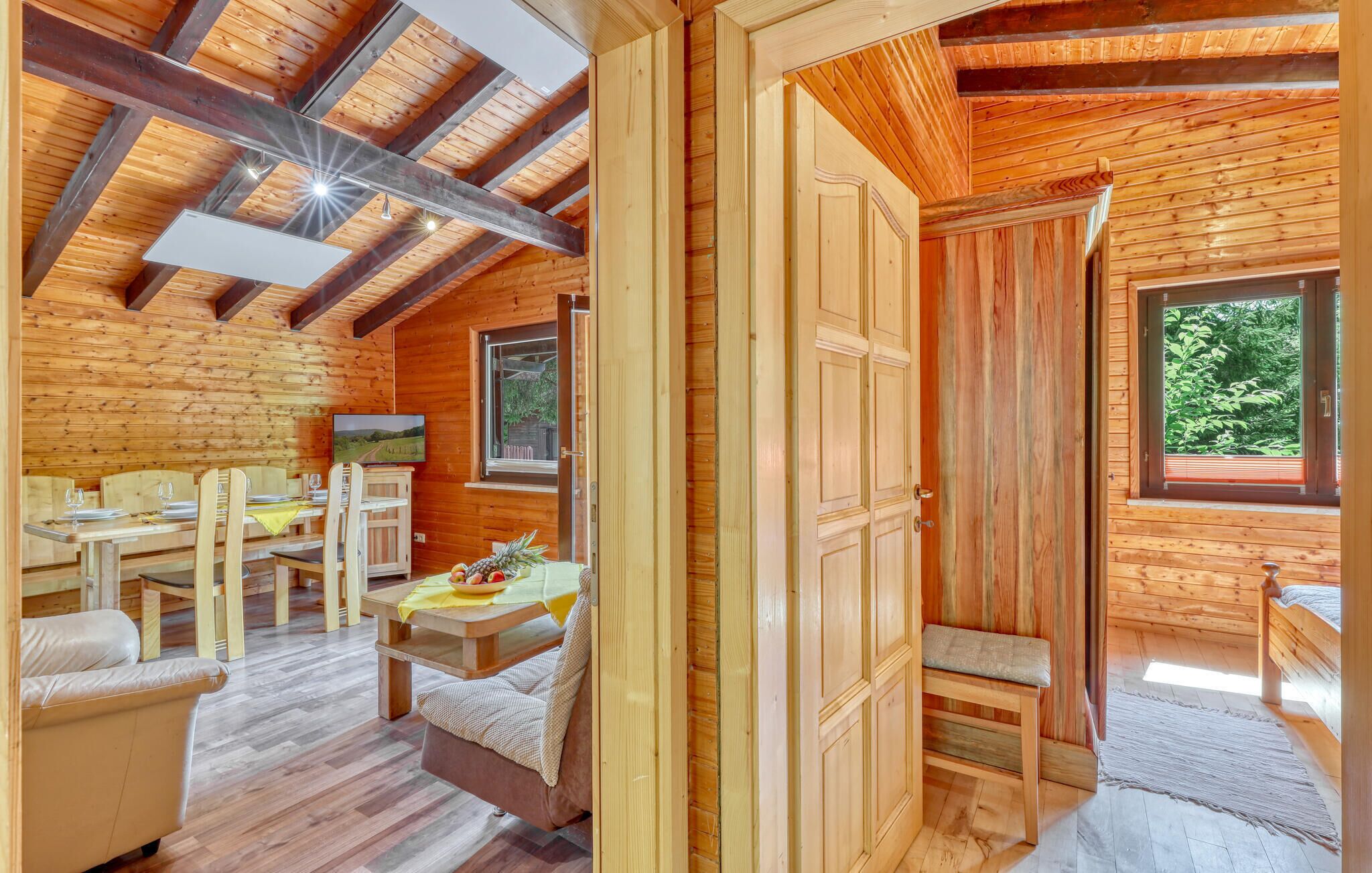 A wooden cabin interior with a dining area, a sofa, and a bed.