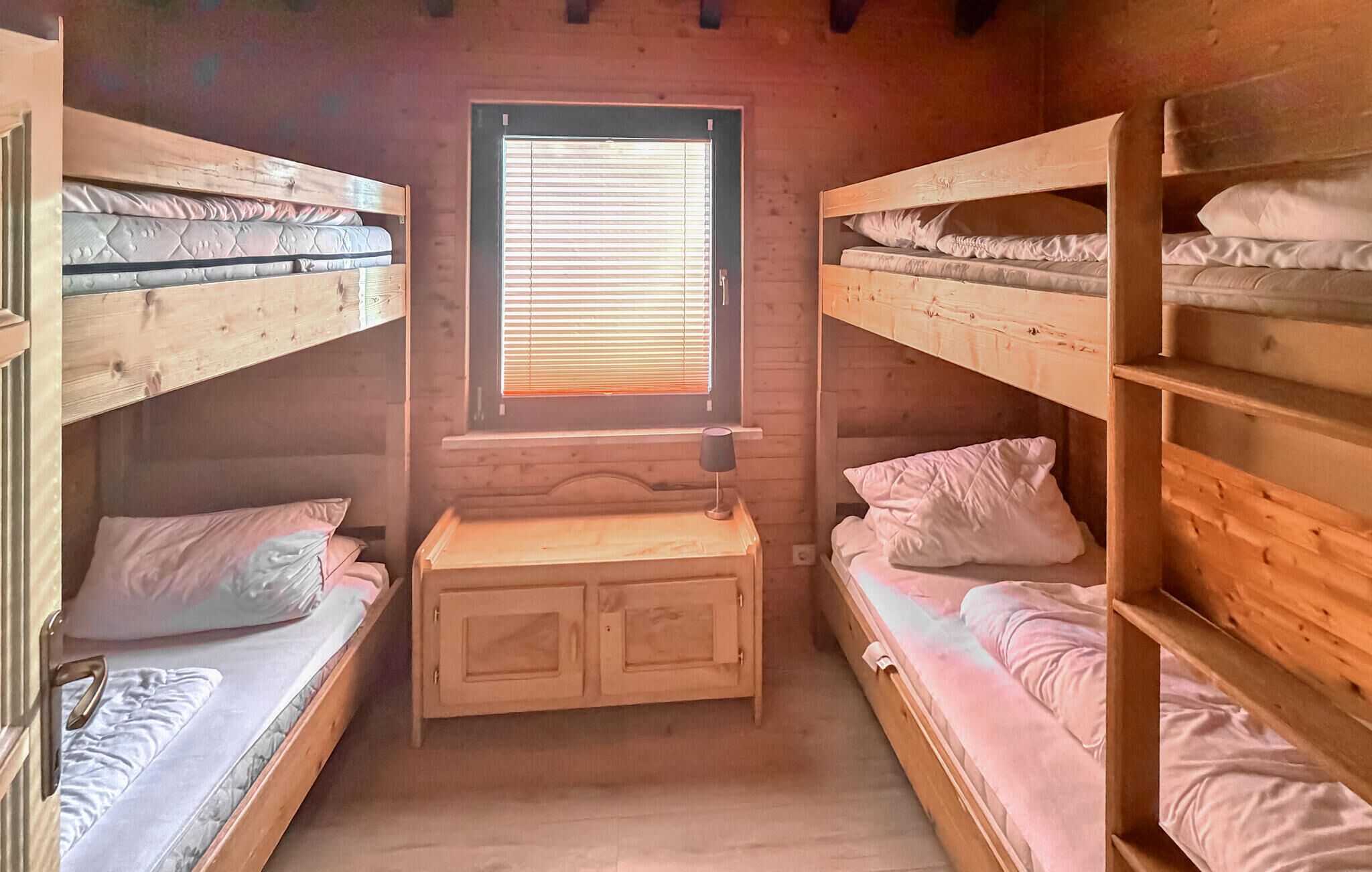 Uma cabana com beliches, uma janela e um pequeno armário de madeira.
