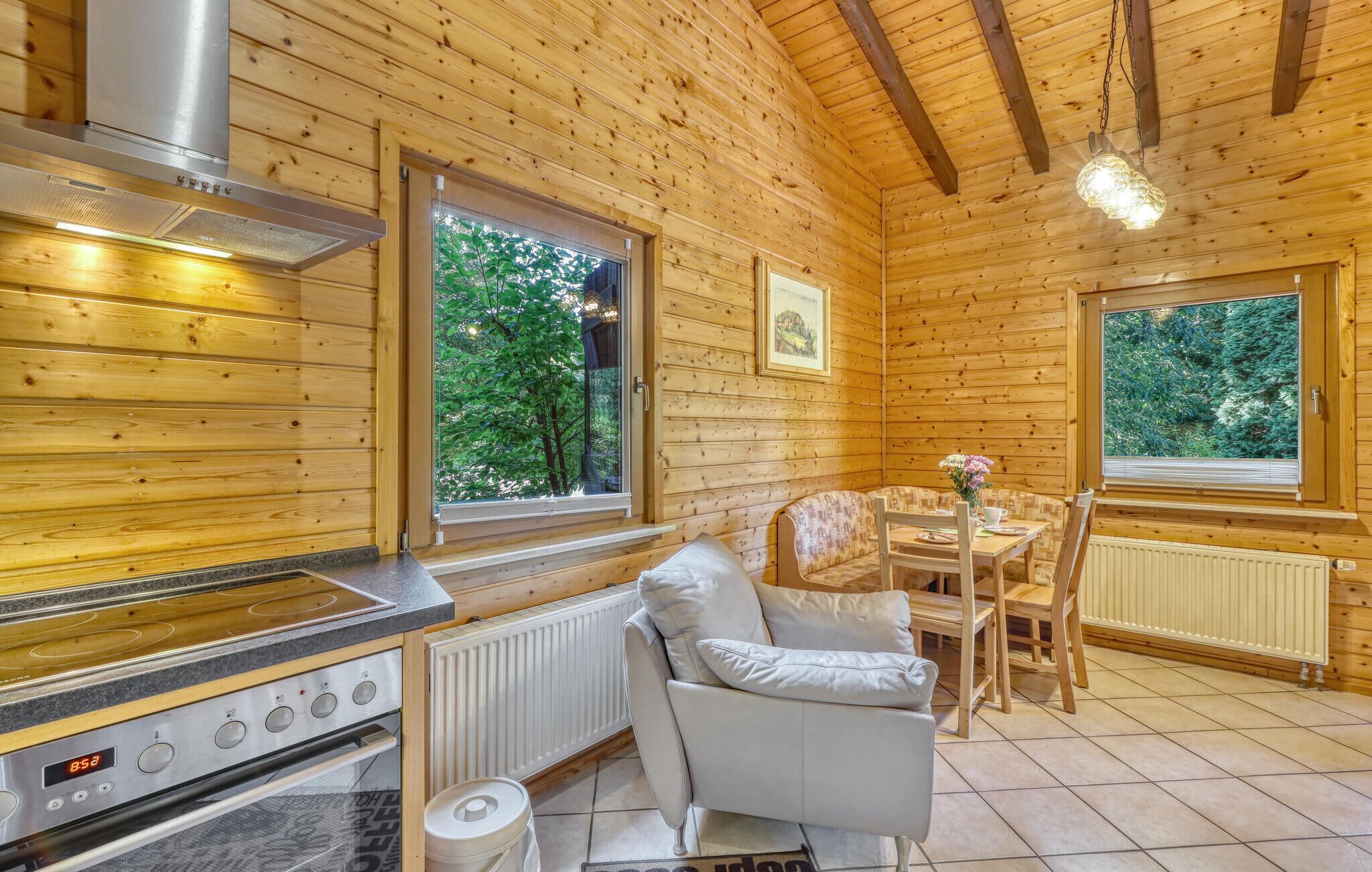 L’intérieur d’un chalet en bois comprend une cuisine, un coin repas et de grandes fenêtres.