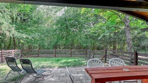 An outdoor patio with a wooden table and chairs, surrounded by a wooden fence and lush greenery. - Nice home in Merzalben with WiFi (Merzalben)