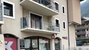 A multi-story building with a ski shop on the ground floor, balconies with metal railings, and a stone-paved entrance. - Chamonix Town Centre Apartment with Free Parking (Chamonix-Mont-Blanc)