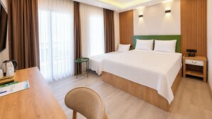 A hotel room with a bed, bedside table, lamp, curtains, and a desk with a chair. - Ovva Inn Yeşilovacık Hotel (Silifke)