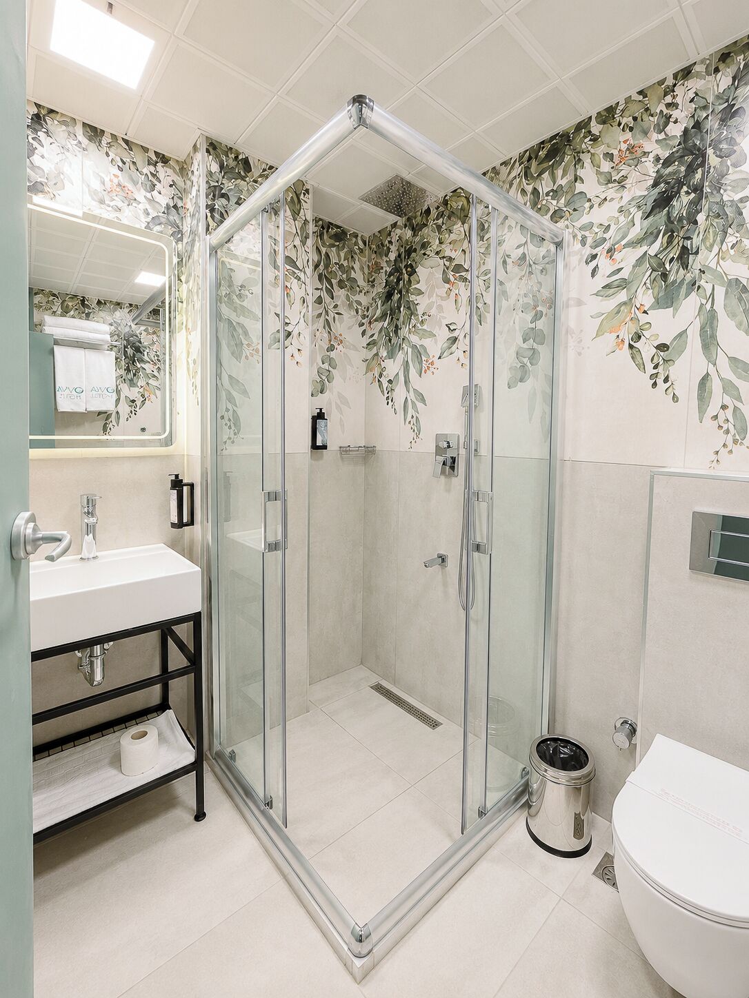 Ein modernes Badezimmer mit einer gläsernen Duschkabine, einem Waschbecken mit Spiegel und einer Toilette.