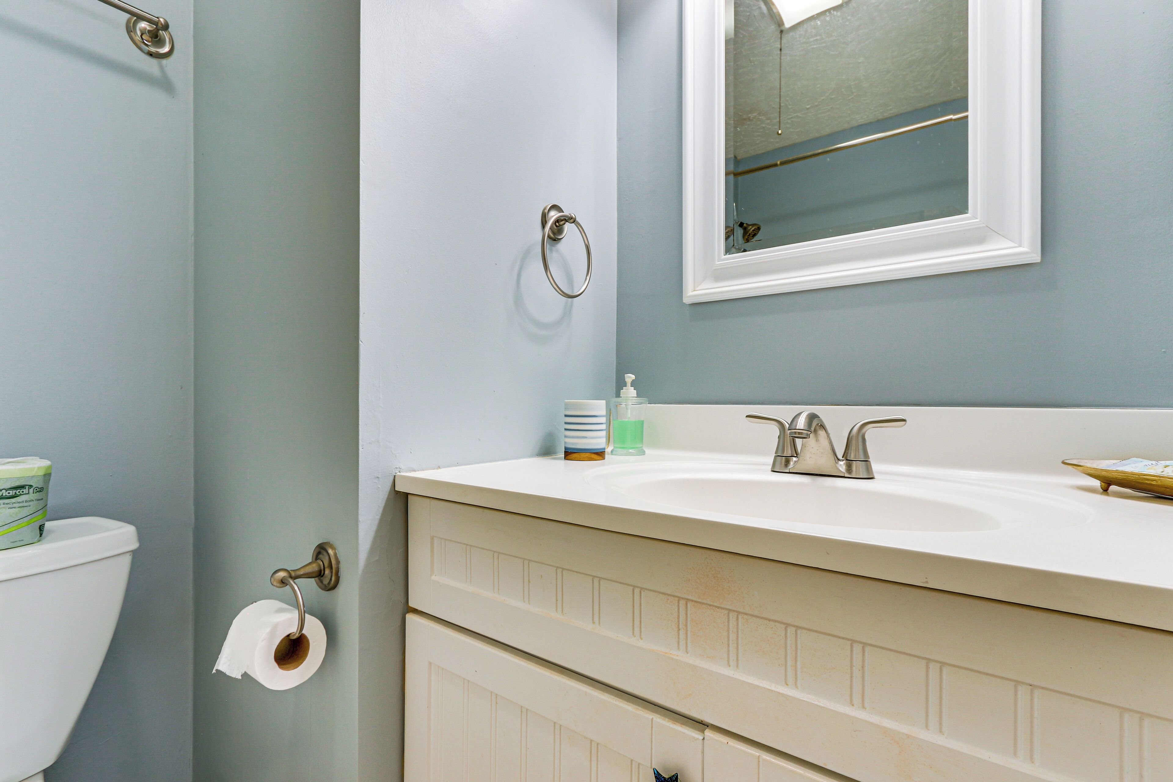 A bathroom with a toilet, sink, and mirror.