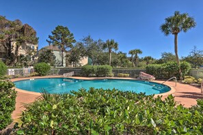 Piscina cercada por vegetação exuberante e um muro branco.