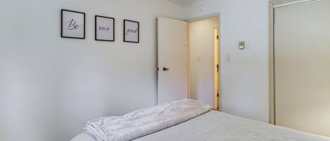 A bedroom with a bed, a ceiling fan, and a door leading to another room.