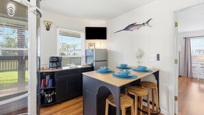 A compact kitchen with a dining area, a flat-screen TV, and a decorative fish on the wall. - Walk to Beach at the End of the Street! (St. Augustine)