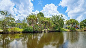 A calm lake with reflections of trees and houses, surrounded by greenery and clear skies. - Scallop HQ: 3 Boat Docks and Free Golf Cart! (Homosassa)