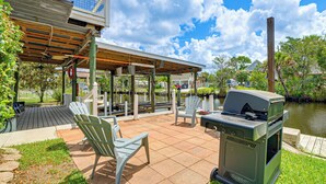 An outdoor patio with a grill, chairs, and a view of a lake. - Scallop HQ: 3 Boat Docks and Free Golf Cart! (Homosassa)