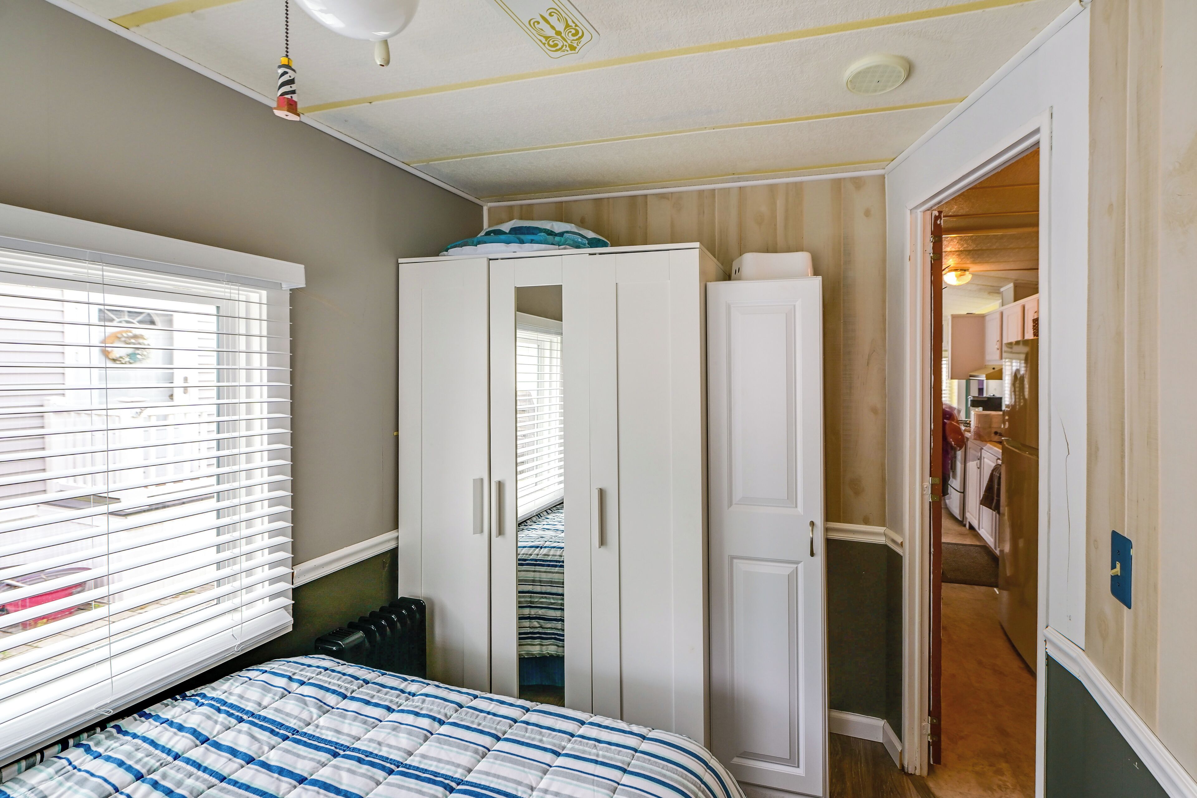 A bedroom with a bed, a wardrobe, and a window with blinds.