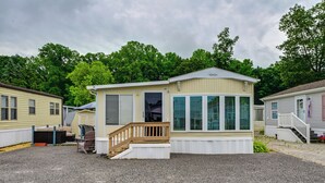 Ein Bungalow mit Veranda, einer kleinen Treppe und einem überdachten Außenbereich.