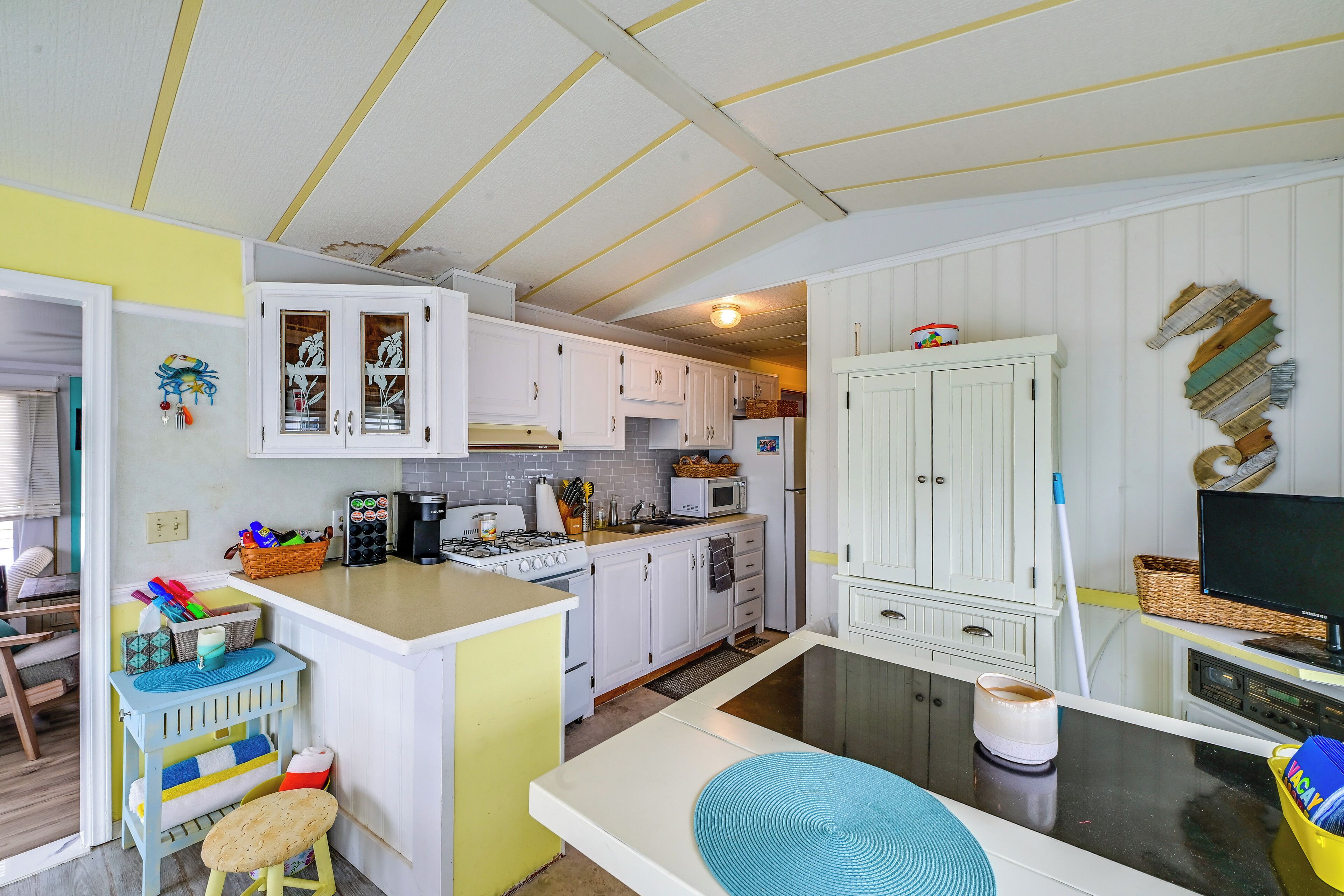 A kitchen with white cabinets, a microwave, a stove, and a dining area with a bench and stools.
