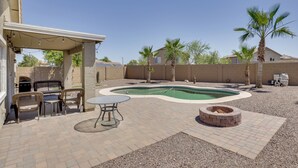 A backyard with a swimming pool, patio furniture, and a fire pit. - Pool, Games, Fenced Yard! Extended Stay in Buckeye (Buckeye)
