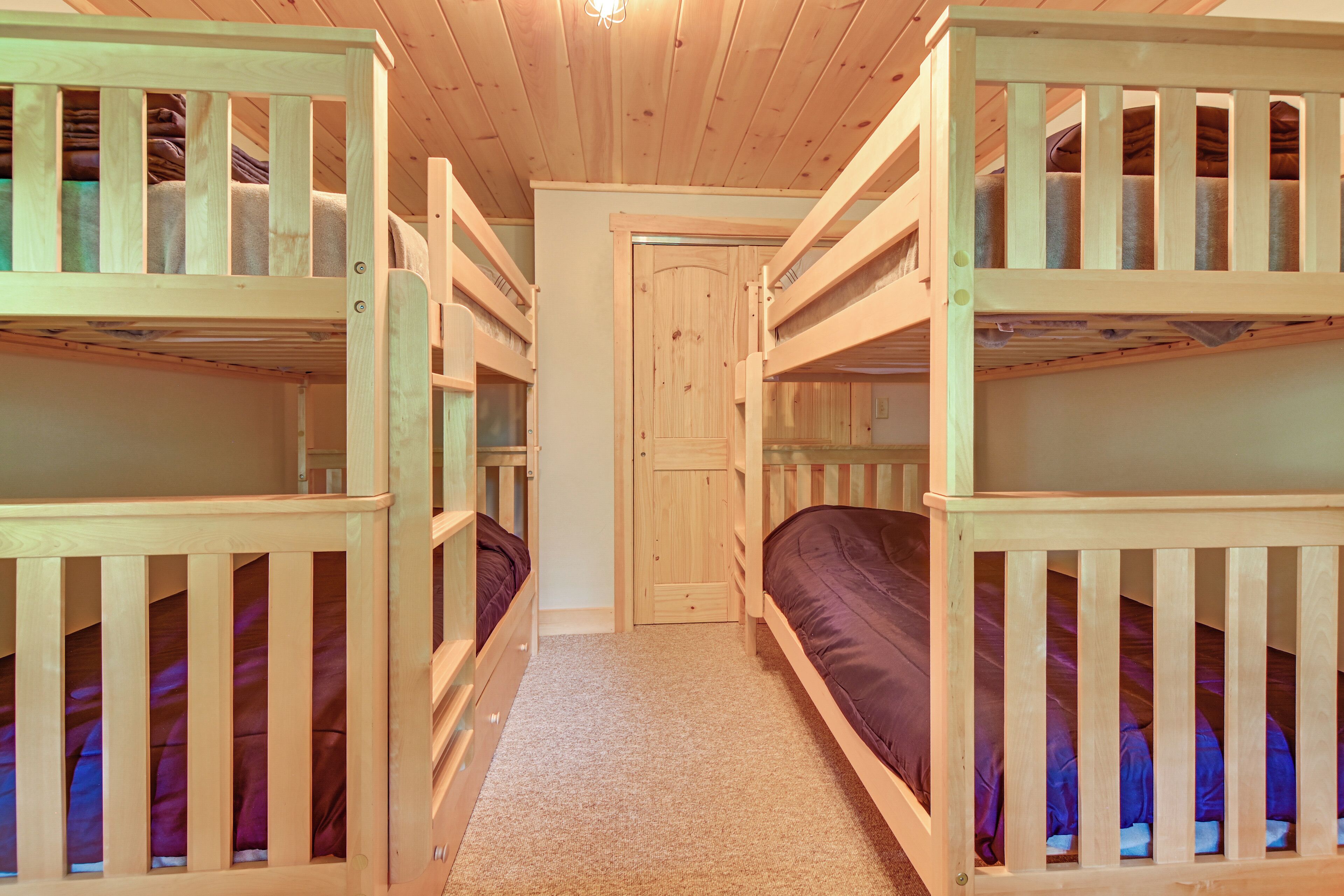 A room with bunk beds, a carpeted floor, and a wooden door.