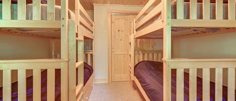 Une chambre avec des lits superposés, un sol recouvert de moquette et une porte en bois.