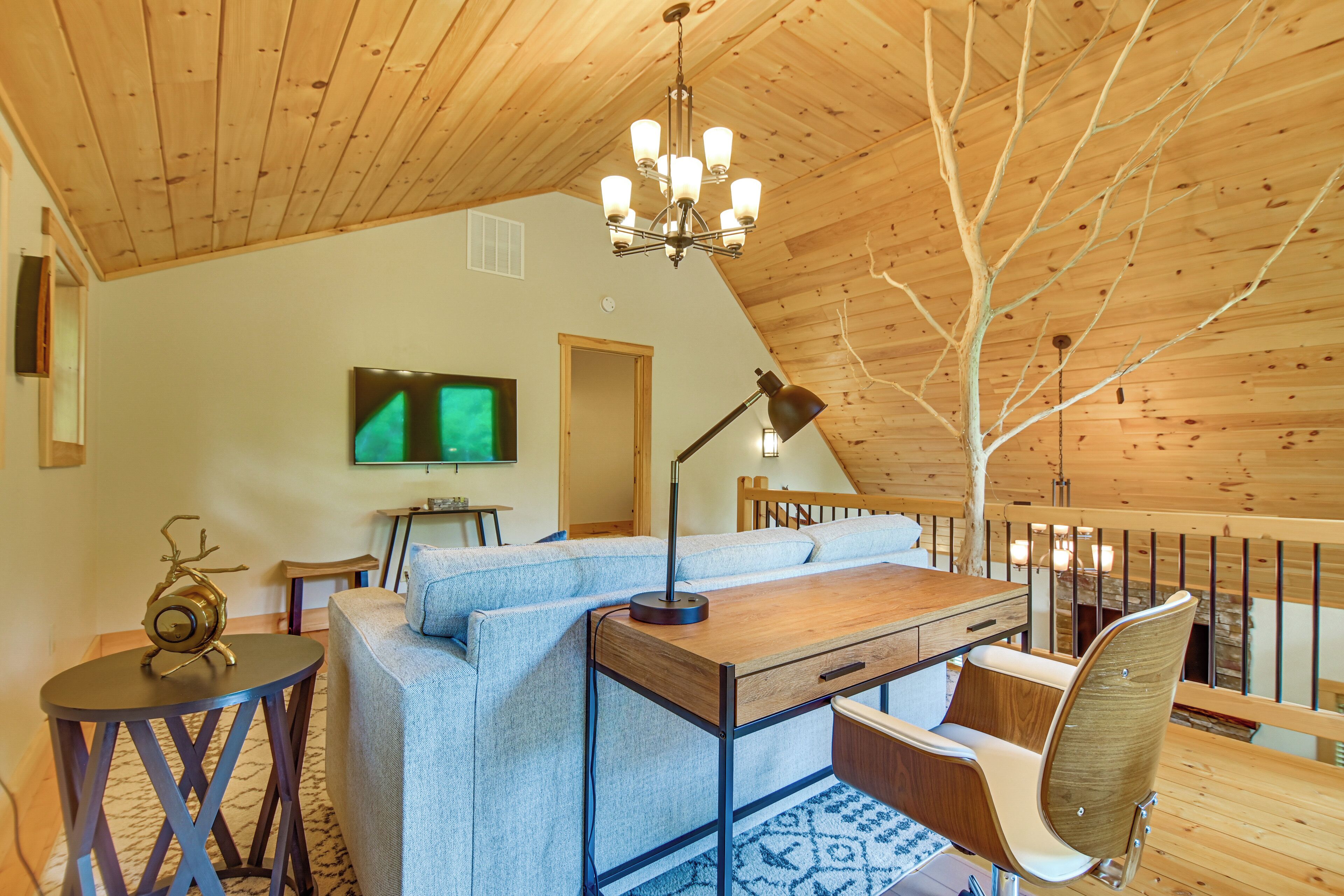Una habitación acogedora con techo de madera, un sofá, una mesa, un televisor y una silla.