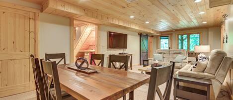 Un interior de madera con una mesa de comedor, sillas, un sofá y un televisor.