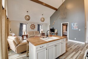 A spacious living area with a wooden dining table, a sofa, and a kitchen with a large island.