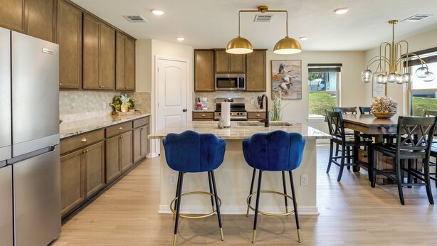 Una cocina moderna con armarios de madera, electrodomésticos de acero inoxidable y taburetes de bar azules.