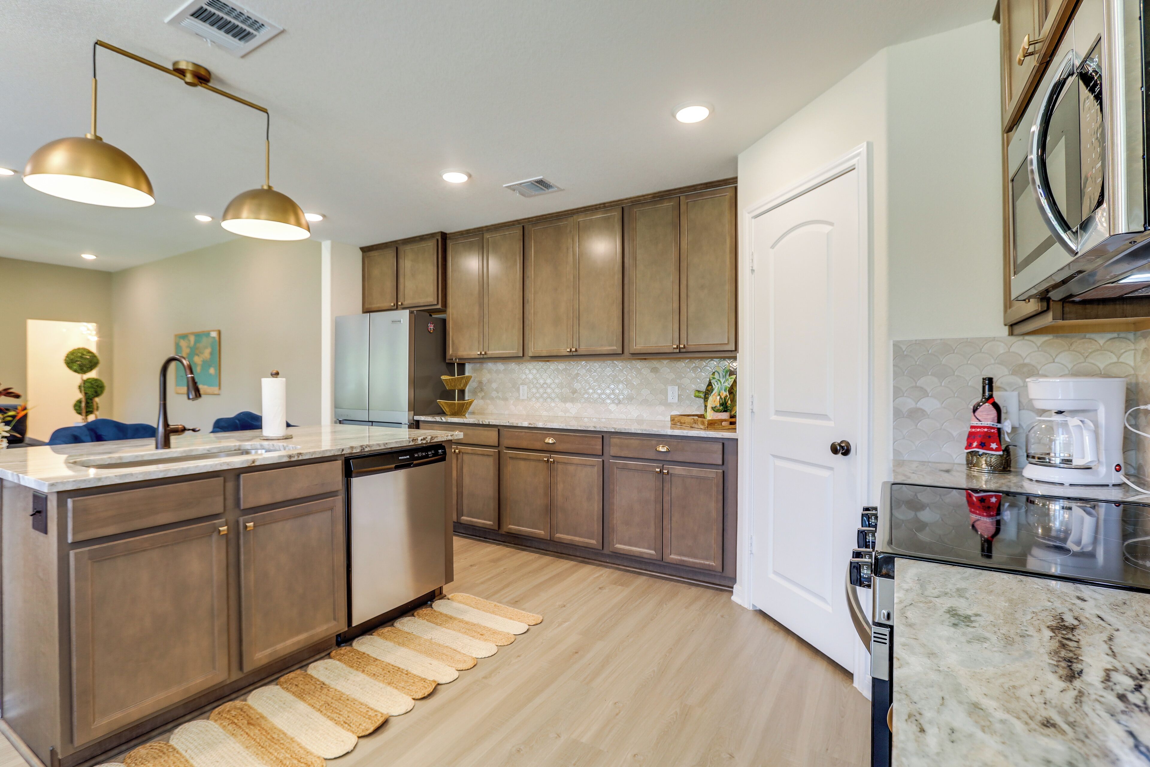 A modern kitchen with wooden cabinets, a dishwasher, a coffee maker, and pendant lighting.