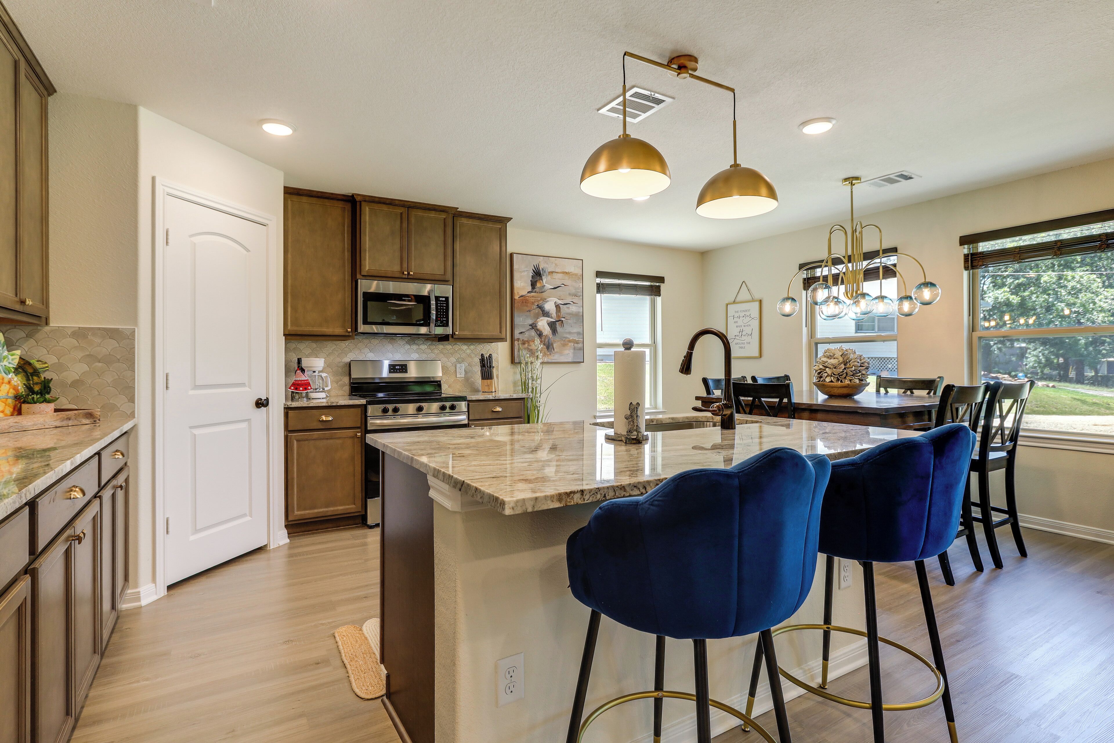 A kitchen with wooden cabinets, a marble island, and blue bar stools.