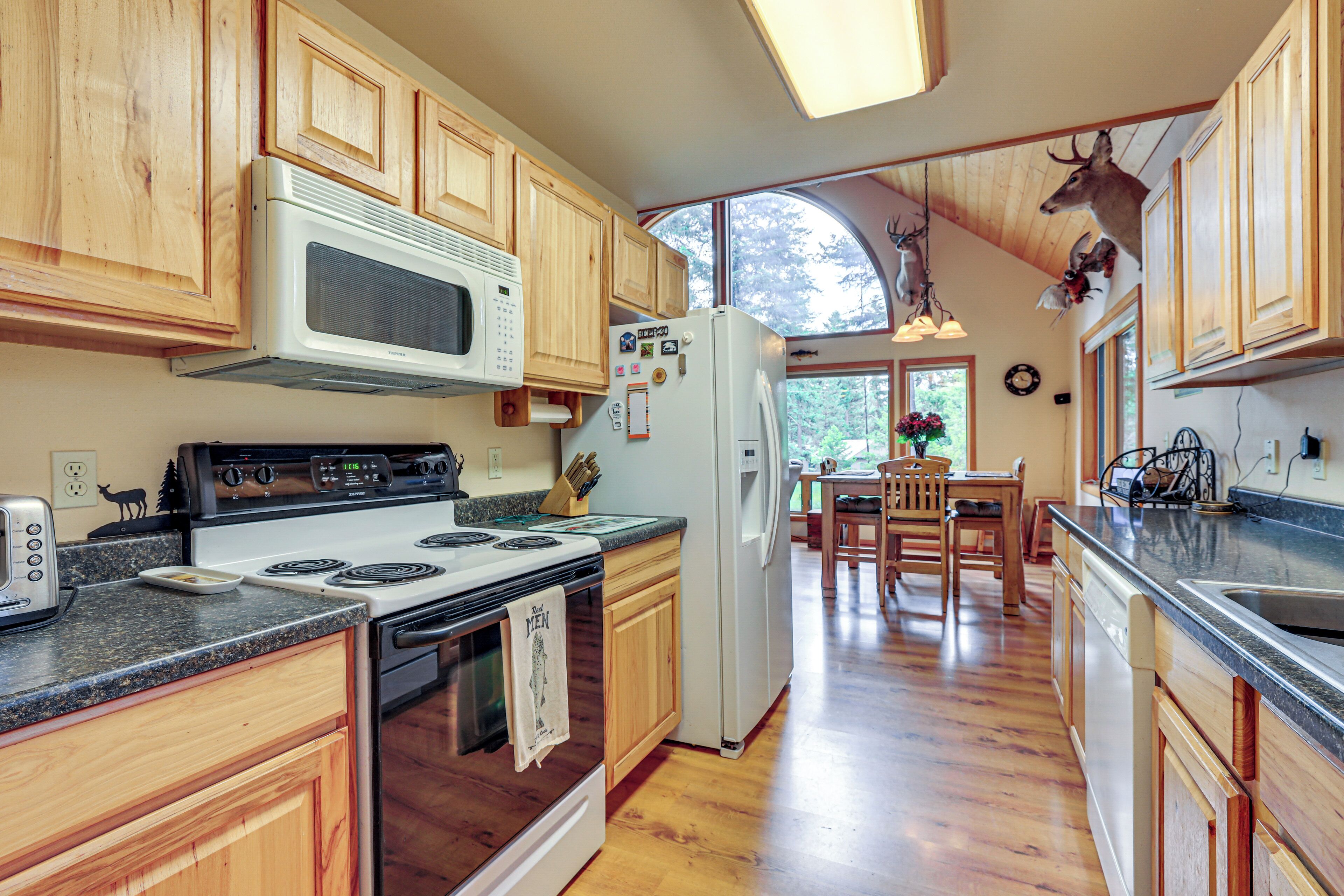 A kitchen with wooden cabinets, a stove, a microwave, and a refrigerator.