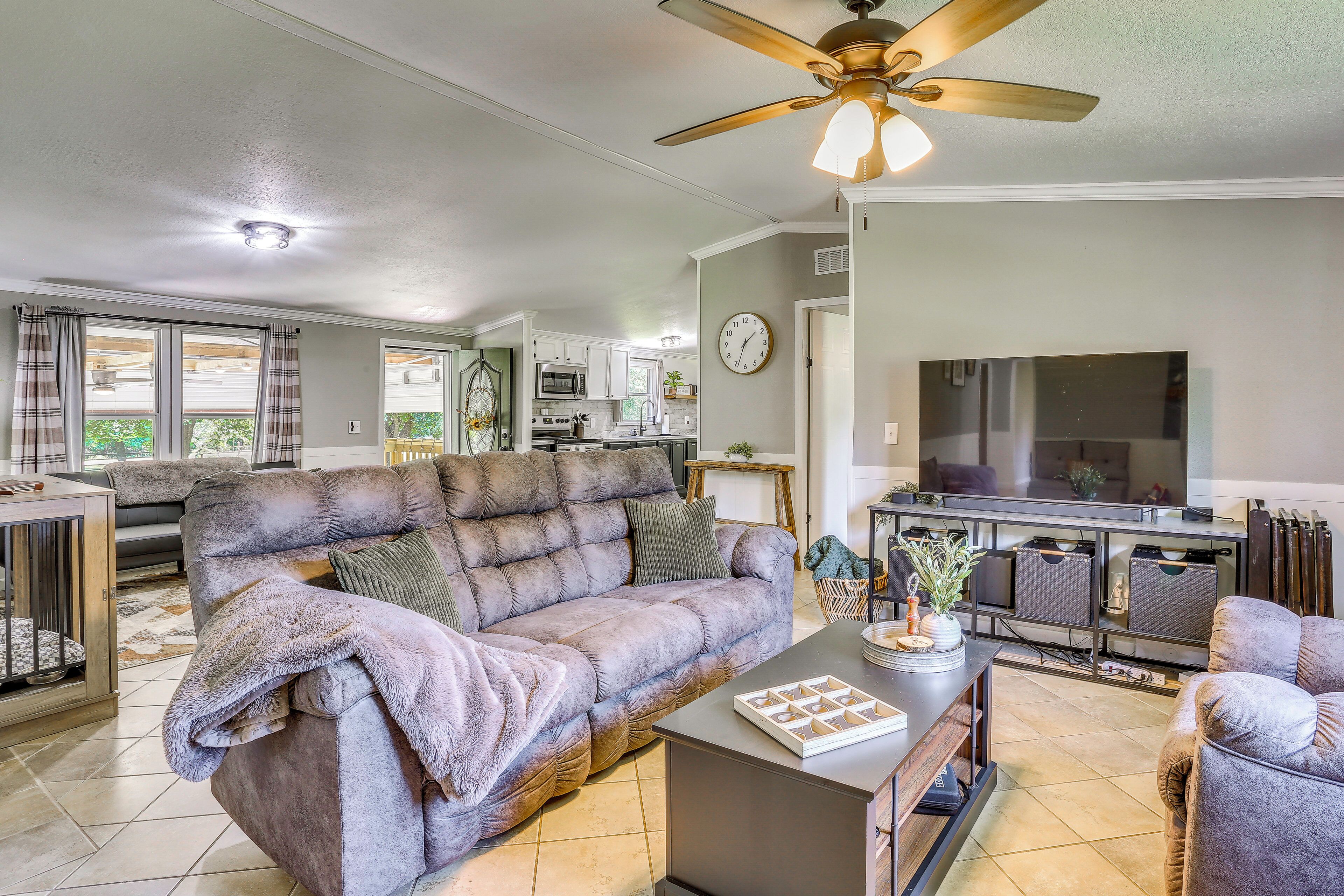 A living room with a sofa, a coffee table, a TV, and a ceiling fan.