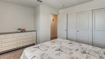 A bedroom with a bed, dresser, and two doors.
