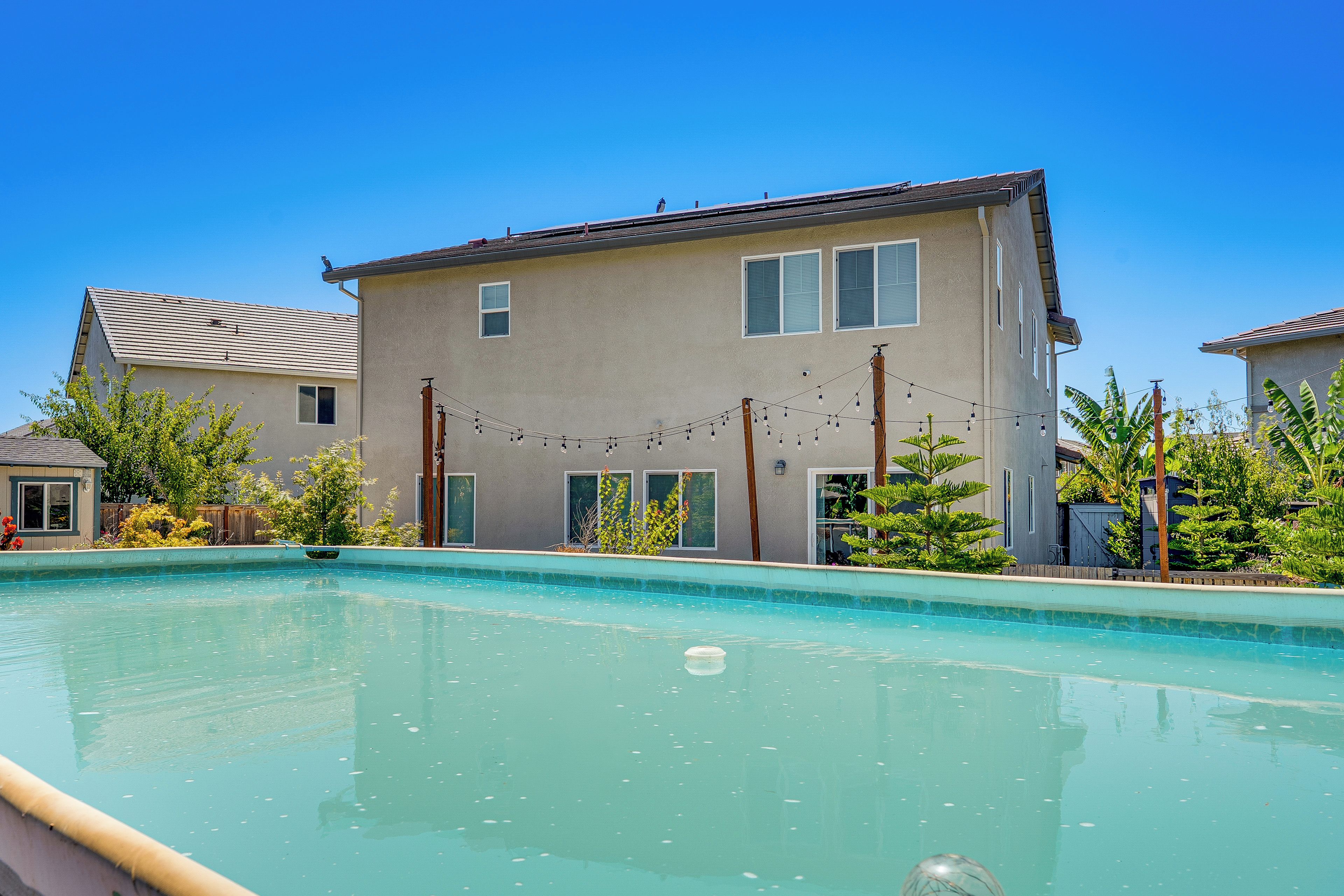A residential swimming pool with a house in the background.
