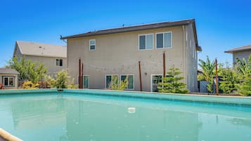 A residential swimming pool with a house in the background.