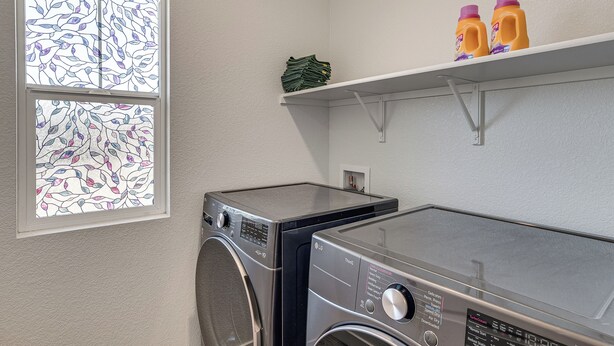 A laundry room with two stacked washers and dryers, a window with stained glass, and a shelf with cleaning supplies. - Private Patio & Yard! Family Getaway in Stockton (Stockton)
