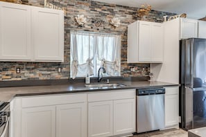 A kitchen with white cabinets, a stainless steel refrigerator, a dishwasher, and a stone backsplash. - Private Pool & Patio! Family Getaway in Stockton (Stockton)