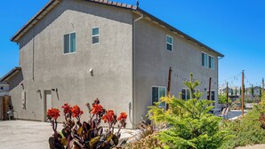 A two-story building with a flat roof, a small porch, and a garden with various plants and flowers. - Private Patio & Yard! Family Getaway in Stockton (Stockton)