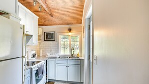 A kitchen with white cabinets, a wooden ceiling, a window, and a sink. - Dual Cottages on Lake of the Ozarks! (Versailles)